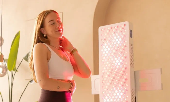 Vrouw staat naast een grote Liroma rood licht therapie lamp